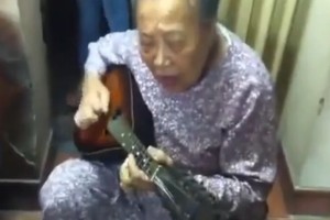 Cụ bà ôm đàn guitar hát một cách hào hùng