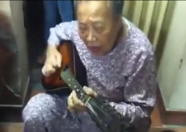 Cụ bà ôm đàn guitar hát một cách hào hùng