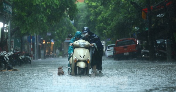 Mưa tầm tã, người dân Hà Nội chật vật ‘bơi qua biển nước’