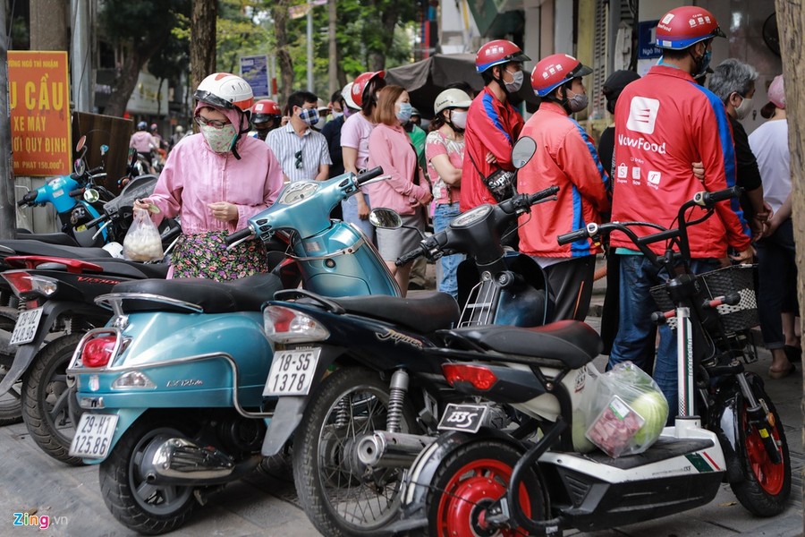 Tại cửa hàng chè nổi tiếng trên đường Ngô Thì Nhậm (quận Hai Bà Trưng, Hà Nội), rất đông người dân và tài xế công nghệ xếp hàng. Họ đứng kín vỉa hè, tràn cả xuống lòng đường. Lực lượng trật tự phải có mặt từ sớm để đảm bảo không xảy ra tình trạng lộn xộn. Anh Nghiêm Hà (tài xế giao hàng) xếp hàng tròn 1 tiếng đồng hồ mới mua được bánh. "Chờ đợi lâu như vậy nhưng giao đơn hàng này tôi chỉ được tổng 16.500 đồng, trừ phí nộp cho công ty còn khoảng 14.000 đồng. Mọi người ngại tiếp xúc nơi đông người nên những người làm công việc giao hàng như tôi đành cố gắng để phục vụ", anh cho biết.