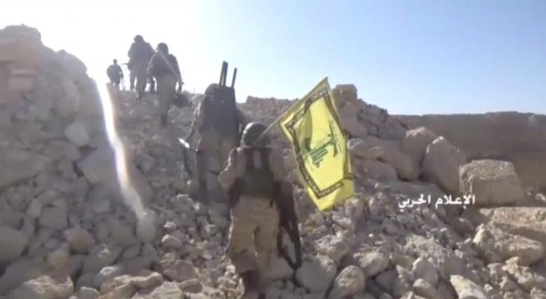 Các chiến binh Hezbollah mang theo cờ của lực lượng này đi qua một địa điểm ở biên giới Syria-Lebanon. Ngày 24/7,  phong trào Hezbollah cho biết cuộc chiến với nhóm Mặt trận al-Nusra tại khu vực này gần như đã kết thúc và yêu cầu các tay súng khủng bố còn lại đầu hàng.