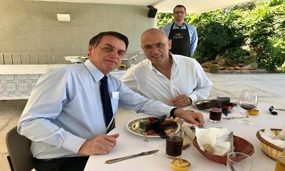 Đại sứ Israel Yossi Shelley (phải) và  Tổng thống Brazil Jair Bolsonaro cùng thưởng thức bữa ăn trước trận đấu bóng đá giữa hai đội tuyển Brazil - Peru vào ngày 7/7. Đại sứ quán Israel tại Brazil sau đó đã đăng tải lên trang cá nhân Twitter bức ảnh ghi lại khoảnh khắc hai người cùng dùng bữa kèm dòng trạng thái cổ vũ đội tuyển Brazil. Đặc biệt trong bức ảnh, đĩa thức ăn của cả hai bị bôi đen.