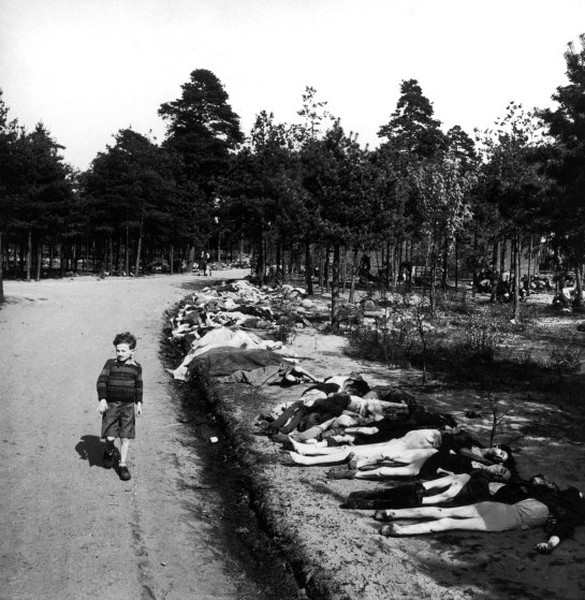 Bé trai đi bộ qua con đường có nhiều xác chết gần trại tập trung Bergen-Belsen năm 1945.