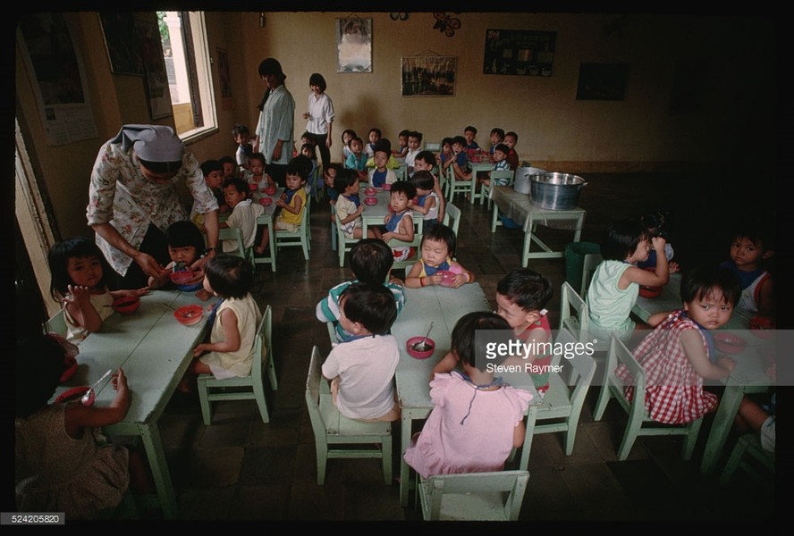 Một ni cô bón thức ăn cho trẻ em tại một lớp học tình thương ở Đà Nẵng, 2/8/1993. Hình ảnh nằm trong loạt ảnh  Việt Nam năm 1993 của nhiếp ảnh gia người Mỹ Steve Raymer - phóng viên ảnh kỳ cựu của tạp chí National Geographic.