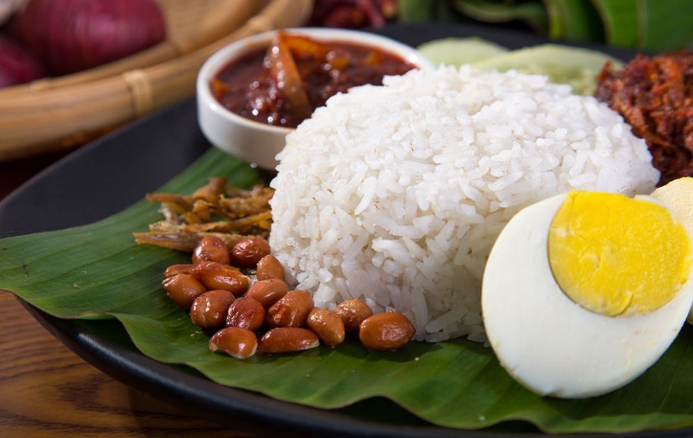 Nasi lemak là tên gọi món  cơm ngon của Malaysia được nấu với nước cốt dừa và lá dứa, ăn với tương ớt sambal, cá trống và lạc rang. Hai món ăn kèm không bắt buộc là trứng và thịt. Ảnh: Theo CNN