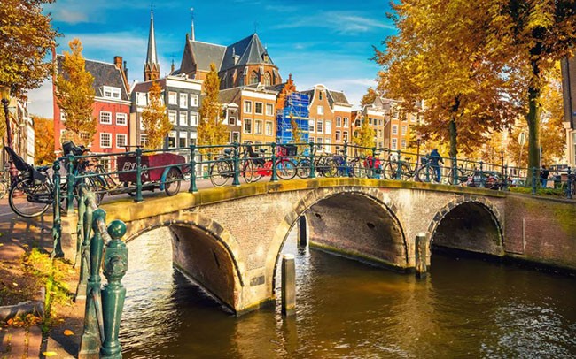 Amsterdam Hãy quên những cánh đồng hoa mùa xuân và những bài hát về hoa tulip: mùa thu chính là thời gian vàng để ghé thăm Amsterdam.  Thành phố trở nên tuyệt vời nhất khi mùa hè nhẹ nhàng biến mất, khi lá cây dọc theo các con kênh rạch đã chuyển sang màu vàng và trong ánh nắng chiều thu nhàn nhạt cả thành phố như được nhuộm trong màu vàng kim long lanh rực rỡ. Lúc này không gì tuyệt hơn được ngồi trong quán cà phê ven đường nhìn ngắm phong cảnh nên thơ, hoặc ghé thăm các cuộc triển lãm tại Bảo tàng Van Gogh. Mùa thu ở Amsterdam thậm chí còn hấp dẫn hơn cả mùa xuân.