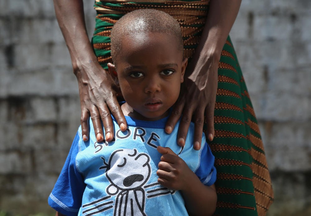 Bé James Mulbah, 2 tuổi đứng cùng mẹ, cô Tamah Mulbah, 28 tuổi người đã nhiễm Ebola và phục hồi sau khi được điều trị và cách ly bởi Tổ chức bác sĩ không biên giới (MSF).