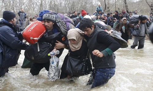 Hàng trăm di dân và người tị nạn tìm cách sang Macedonia sau nhiều tiếng chờ đợi trong cơn mưa tầm tã và lội qua một dòng sông. Rất nhiều người vác đồ đạc và trẻ nhỏ trên vai khi lội qua sông.