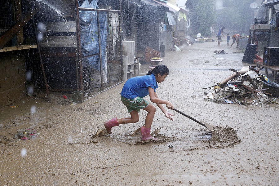 Mưa lũ những ngày qua tại Philippines đã khiến ít nhất 5 người thiệt mạng và hàng chục nghìn người khác phải tạm rời bỏ nhà cửa. Ảnh: Một cư dân dọn bùn trên đường phố ở San Mateo, tỉnh Rizal, hôm 14/8.