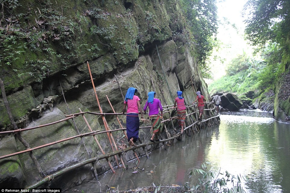 Ngôi làng của những  bộ lạc ở Bangladesh này nằm sâu trong những quả đồi ở huyện Bandarban. Họ vẫn duy trì lối sống truyền thống và tách biệt với thế giới hiện đại. Ảnh: Những người phụ nữ bản địa ở Bangladesh đi qua một cây cầu tạm bợ để lấy nước từ một con suối trên đồi.