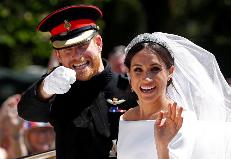 Hoàng tử Anh Harry và cô dâu Meghan Markle cười tươi vẫy chào mọi người khi ngồi trên xe ngựa sau lễ cưới diễn ra tại thánh đường St George, Lâu đài Windsor, ngày 19/5. (Nguồn ảnh: Reuters)