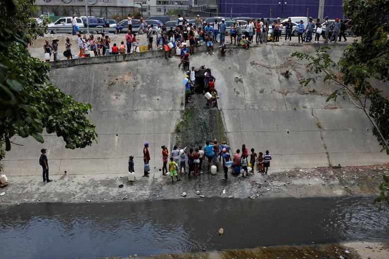 Theo hãng thông tấn Reuters, tình trạng mất điện nhiều ngày qua đã khiến người dân Venezuela lâm vào tình cảnh thiếu nước trầm trọng. Hàng chục người dân đã đổ ra sông Guaire để lấy nước mang về sử dụng. (Nguồn ảnh: Reuters)