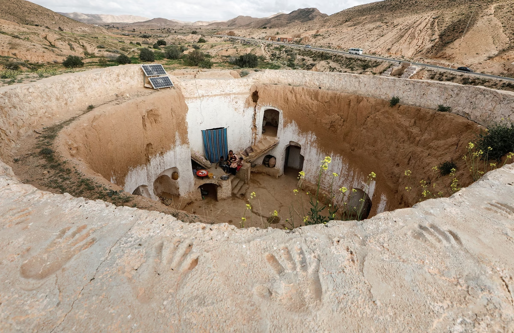 Saliha Mohamedi, khi đó 36 tuổi, ngồi cùng các con tại  ngôi nhà dưới lòng đất troglodyte của họ ở ngoại ô Matmata, Tunisia, vào ngày 4/2/2018. "Tôi không muốn rời khỏi ngôi nhà này, bởi như thế cũng giống như tôi đang vứt bỏ cuộc sống và truyền thống của mình vậy", Saliha chia sẻ. (Nguồn ảnh: Reuters/Atlantic)