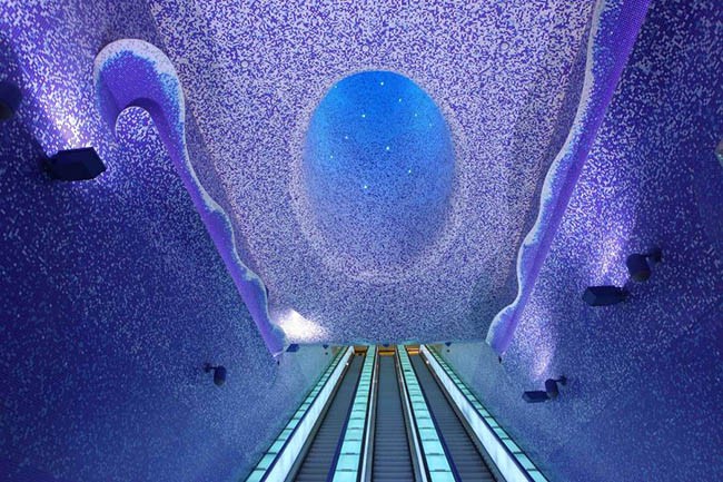 Ga Toledo Metro Station, Naples, Ý: Nhà ga Toledo (Naples, Ý) , nhà ga tuyệt đẹp này được thiết kế bởi kiến trúc sư người Canada Oscar Tusquets và khánh thành năm 2012. Được ghép phối hai màu xanh và trắng, nhà  ga tàu điện tạo cảm giác như những bậc thang sẽ đưa bạn lên chín tầng mây.