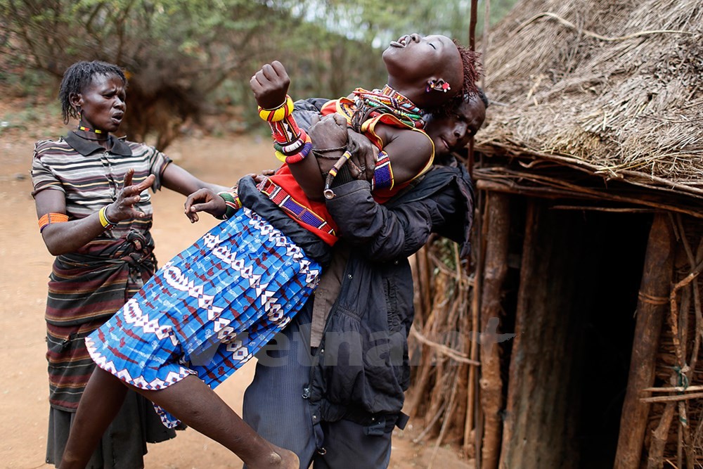 Một người đàn ông giữ cho cô bé không vùng vẫy khi cô cố chạy trốn. (Ảnh: Siegfried Modola/Reuters).