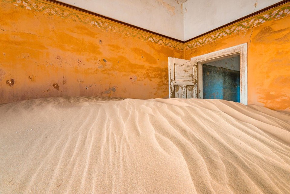 Kolmanskop, Namibia: Nằm giữa sa mạc Namib, Kolmanskop được xây dựng làm nơi ở cho công nhân của mỏ kim cương gần đó.  Thị trấn bị bỏ hoang vào giữa những năm 1950, khi kim cương ở đây trở nên khan hiếm, và kể từ đó Kolmanskop dần chìm trong biển cát sa mạc. Ảnh: Alex Treadway/National Geographic.