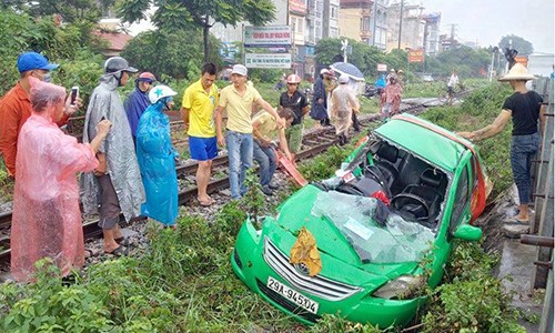 Xe taxi biến dạng tả tơi sau khi bị tàu hỏa kéo lê ở Hà Nội