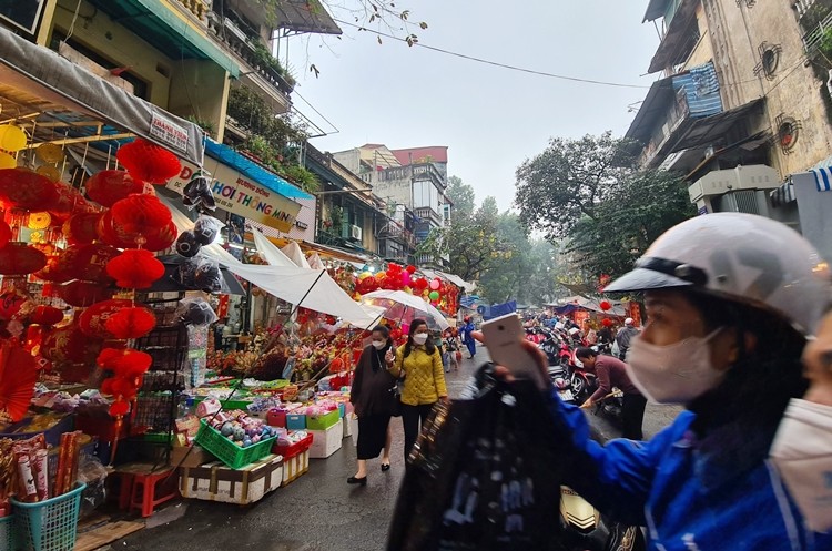 Chiều ngày 21/1/2022, thời tiết ở Hà Nội có mưa rào nhưng nhiều người vẫn che ô, mặc áo mưa kéo kéo nhau đến phố Hàng Mã để mua sắm đồ trang trí Tết Nguyên đán Nhâm Dần 2022.