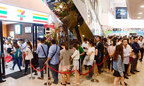 Cửa hàng  7-Eleven nằm trong tòa nhà Saigon Trade Center nơi tập trung nhiều văn phòng ở quận 1. Tranh thủ trước giờ làm việc, nhiều người xếp hàng mua sản phẩm ưu đãi tại cửa hàng mới khai trương.