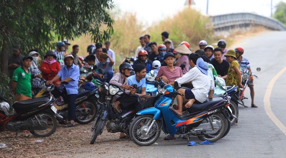 Trưa 31/1, hàng trăm người hiếu kỳ tập trung tại khu vực giáp ranh giữa xã Trung An - xã Phú Hòa Đông, huyện Củ Chi, TP.HCM. Đây là nơi hơn 500 cảnh sát được điều động vây bắt  nghi can Lê Quốc Tuấn, người gây ra vụ nổ súng khiến 4 người chết tại sới bạc và 1 người chết trên đường gã này bỏ trốn.