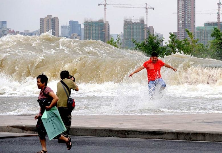 Một người đàn ông chụp ảnh sóng thủy triều dâng cao qua bờ sông Tiền Đường. Do ảnh hưởng của hiện tượng siêu Trăng, thủy triều trên sông Tiền Đường năm nay gây ra những đợt sóng cao và mạnh hơn.