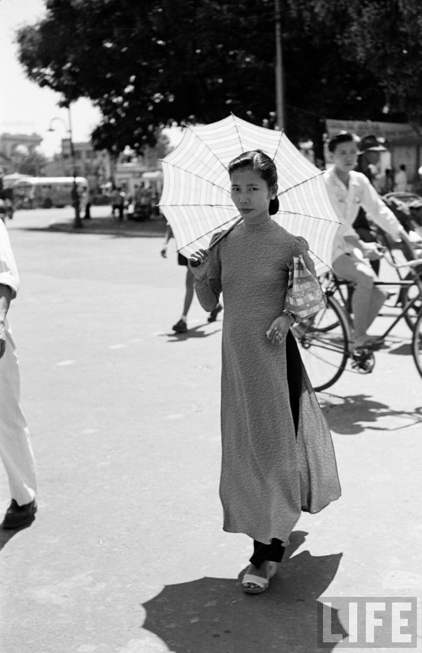 Thiếu nữ áo dài che ô để bảo vệ mình trước cái nắng của  Sài Gòn năm 1950. Ảnh: Carl Mydans/ Life.