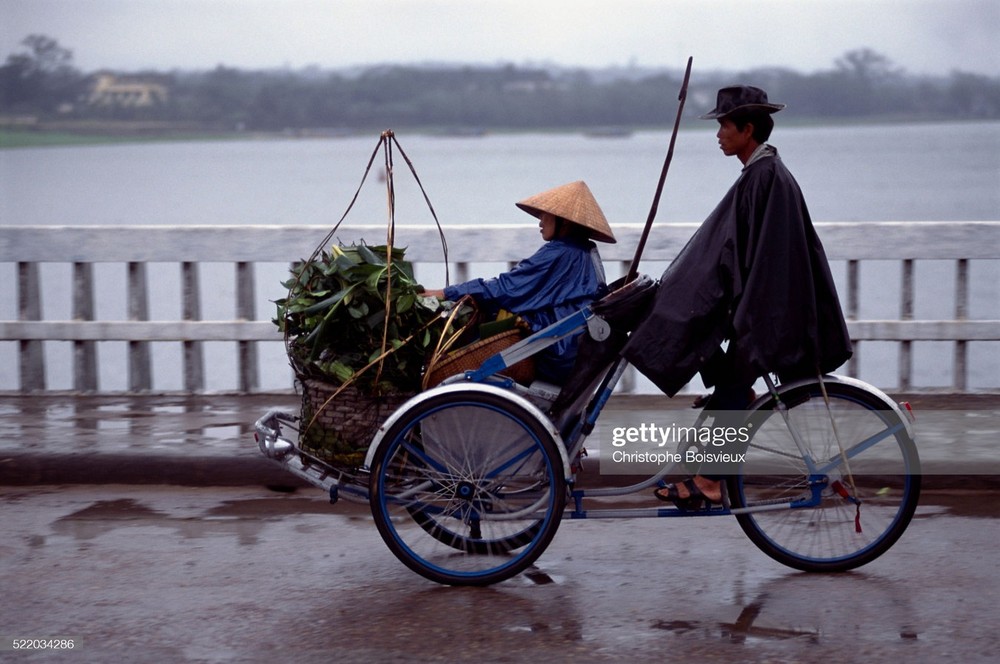 Chuyến xích lô ngày mưa bên sông Hương, Cố đô Huế. Ảnh: Christophe Boisvieux/ Getty Images.