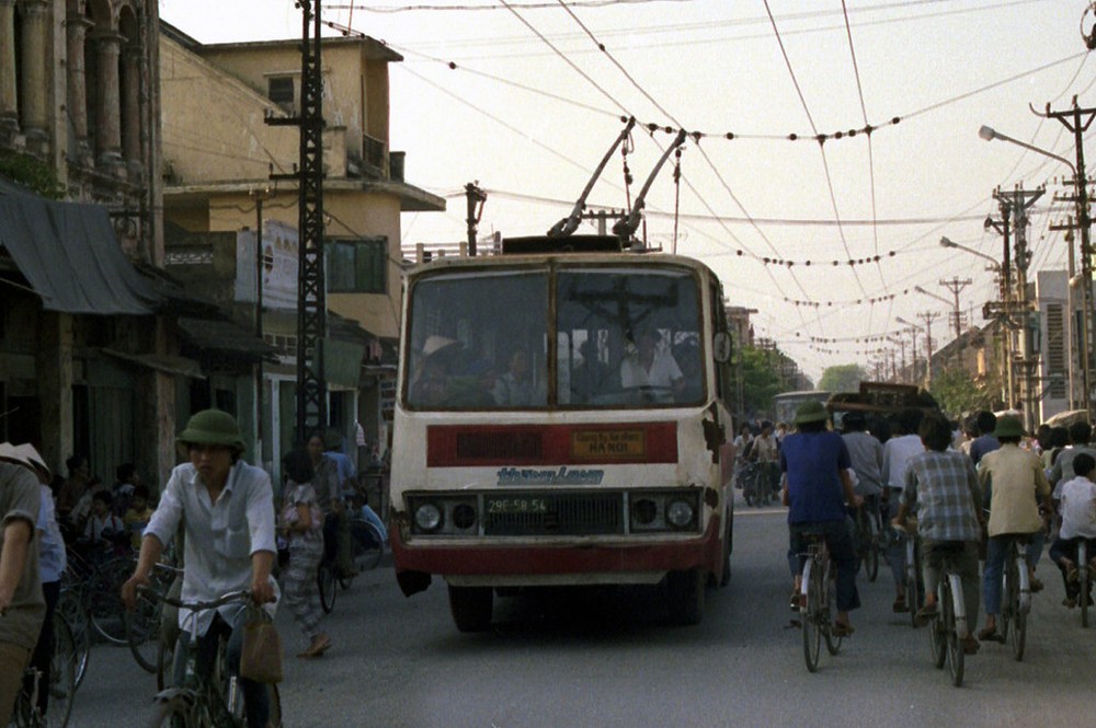  Tàu điện bánh hơi chạy trên đường phố Hà Nội năm 1990. Cùng với tàu điện chạy trên ray, tàu điện bánh hơi từng là một loại hình phương tiện giao thông công cộng độc đáo ở Hà Nội những năm cuối thập niên 1980, đầu 1990. Ảnh: Ian Lynas Flickr.