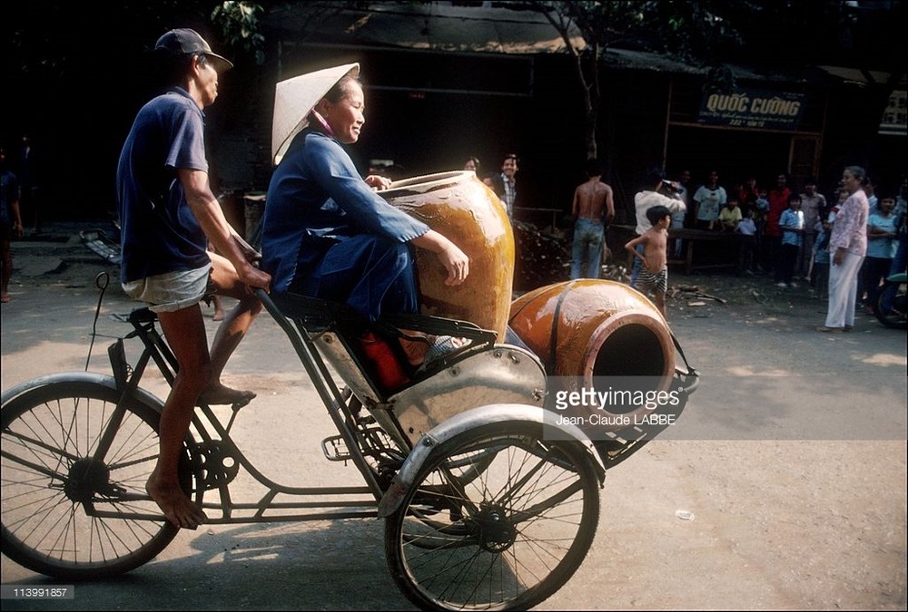 Chuyến xích lô chở cụ bà và những vại nước lớn,  TP. HCM năm 1991. Ảnh: Jean-Claude Labbe/Getty Images