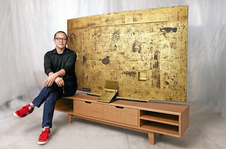 Tác giả đang ngồi cạnh chiếc TV Ultra HD 4K 78-inch Gold Edition của Samsung, được trang trí giống như một tác phẩm nghệ thuật.