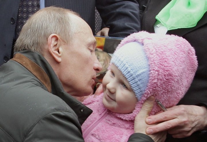 Ông Putin âu yếm hôn má một em nhỏ khi ông ghé thăm một địa điểm gần St. Peterburg năm 2014. AFP