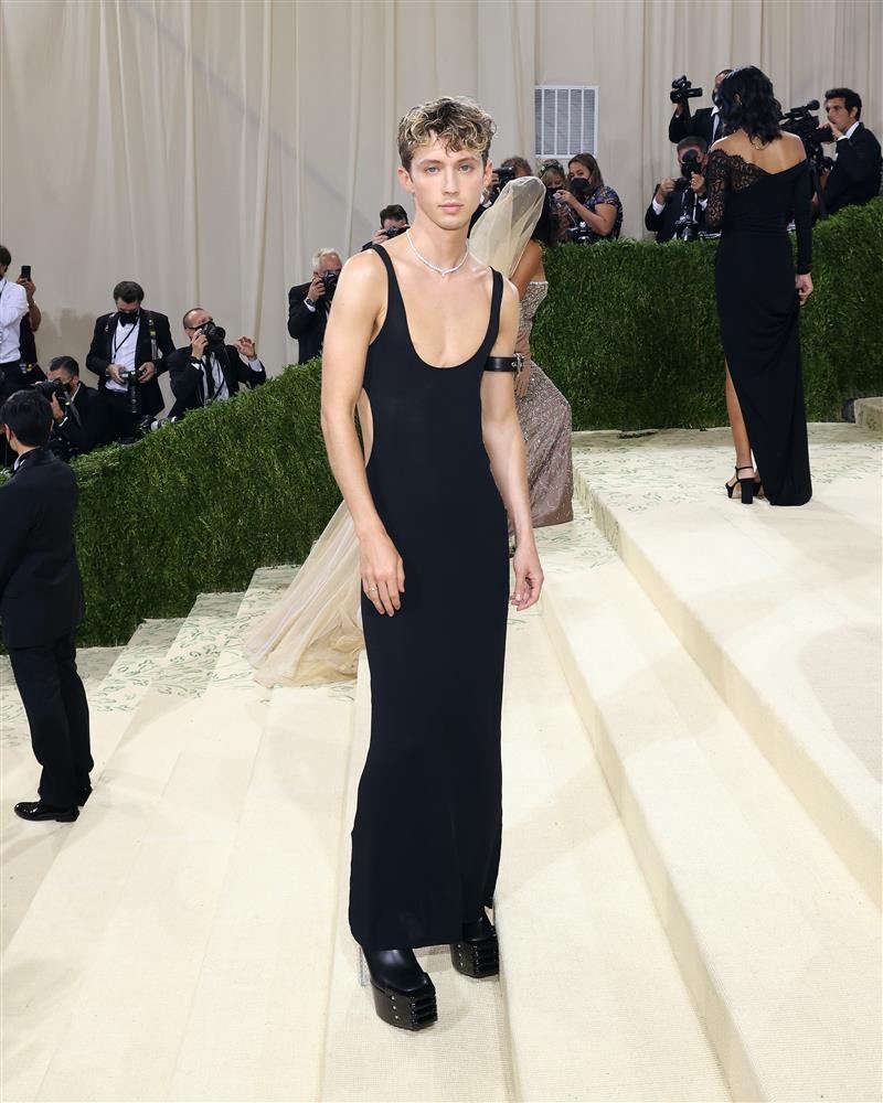 Tại Met Gala năm nay, Troye Sivan chơi lớn khi mặc chiếc váy dệt kim màu đen 2 dây dài thượt, cut-out bên hông mix cùng vòng cổ kim cương của Cartier và vòng da đeo ở bắp tay.