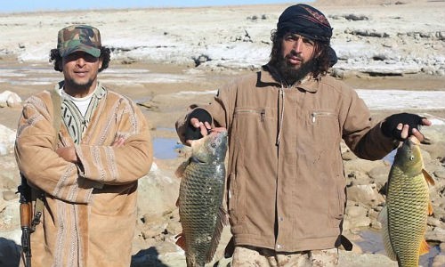  Chiến binh IS khoe chiến lợi phẩm là hai chú cá lớn vừa bắt ở sông Euphrates. Một chiến binh vẫn đeo súng máy tự động bên người.