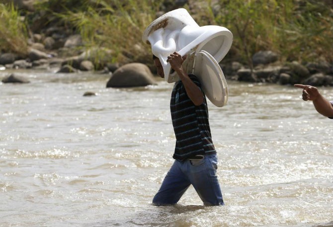 Một người đàn ông vác bồn cầu vượt qua sông Tachira ở biên giới để trở về Colombia ngày 27/8/2015. Cuộc  khủng hoảng biên giới đã ảnh hưởng đến cuộc sống của nhiều người dân Colombia.