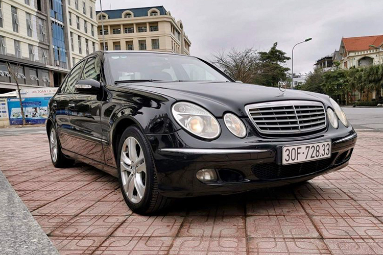 Mercedes-Benz E220 đời 2005 sở hữu thiết kế truyền thống của hãng xe Đức, đầu xe với lưới tản nhiệt mạ crôm tinh tế đi cùng với cụm đèn pha bi-xenon hình tròn nổi tiếng của “Mẹc”. Cụm đèn pha này sử dụng hệ thống chiếu sáng chủ động tự liếc khi đánh lái giúp mở rộng tầm chiếu sáng.