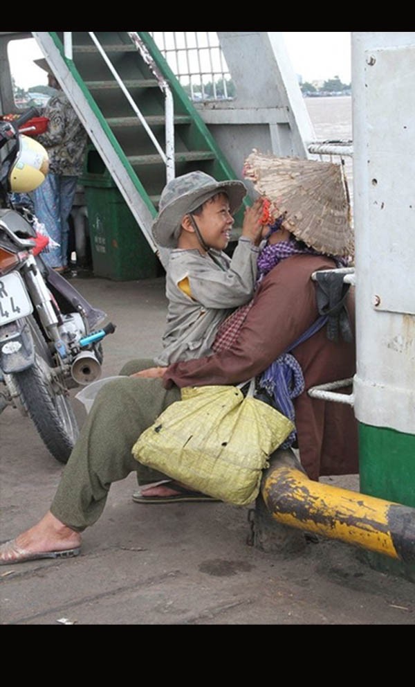 Bức ảnh đang được lan truyền trên mạng kèm theo chú thích: "Hai bà cháu xin ăn trên phà Vàm Cống (An Giang), mẹ của bé đi xuất khẩu lao động và không trở về...". Trong ảnh là một cậu bé đang cười đùa hồn nhiên, vui vẻ bên cạnh người bà đã già, đội chiếc nón lá rách. Bức ảnh nhận được sự quan tâm của đông đảo người xem cùng với nhiều bình luận bày tỏ sự xúc động trước hoàn cảnh sống của hai nhân vật. "Nhìn nụ cười của em mà thấy thương em quá! Em cười vì em cũng không biết em đang trong hoàn cảnh nào? Cố lên em! Gia đình em sẽ sớm được đoàn tụ...", nickname Chuột Duy bày tỏ.