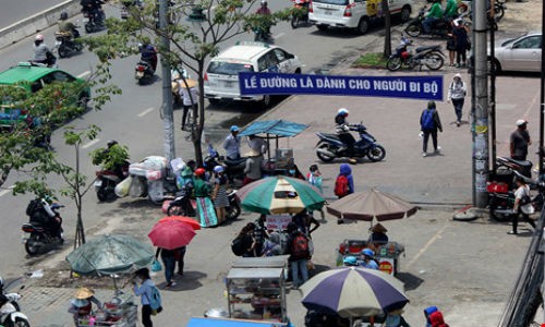  Vỉa hè đường Điện Biên Phủ, phía trước trường Đại học Hutech bị hàng chục người bán hàng rong lấn chiếm dù phía trên có treo băng rôn "Lề đường là dành cho người đi bộ".