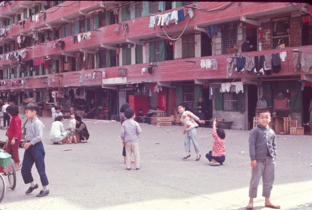 Một nhóm trẻ em vui đùa tại sân phía trước một tòa chung cư ở  Hong Kong những năm 1960.