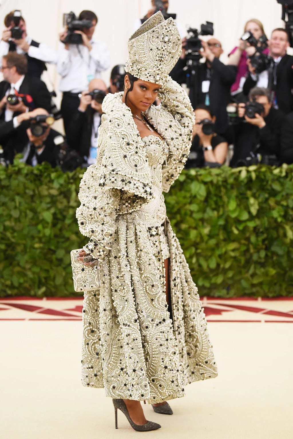 Rihanna gây ấn tượng với thời trang thảm đỏ tại Met Gala năm 2018. Cô đã diện bộ cánh thể hiện đúng tinh thần tôn giáo với những chi tiết đậm chất kiến trúc Gothic được đính đá cẩn thận. Ngoài ra, điểm nhấn của trang phục là chiếc mũ lấy cảm hứng từ vương miện của Đức giáo hoàng.