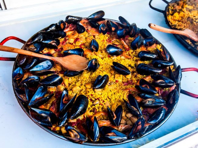 1. Paella (cơm chiên hải sản), Tây Ban Nha: Đây là món truyền thống của Tây Ban Nha có nguồn gốc từ vùng Valencia. Nó bao gồm cơm, hải sản và rau được bày trong một chiếc đĩa lớn.