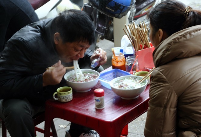 Xì xụp phở sáng: Thưởng thức phở trong bữa sáng ngày lạnh là thói quen của không ít người. Đặc biệt, giữa  mùa rét Hà Nội được húp một bát phở nóng hổi, ăn từng miếng đậm đà và xuýt xoa là một điều khiến nhiều người nhớ mãi khi rời xa Hà Nội. Ảnh: AFP-JIJI.