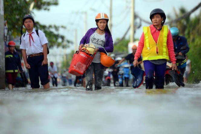 Công nhân, học sinh vất vả giữa dòng nước ngập - Ảnh: HỮU KHOA