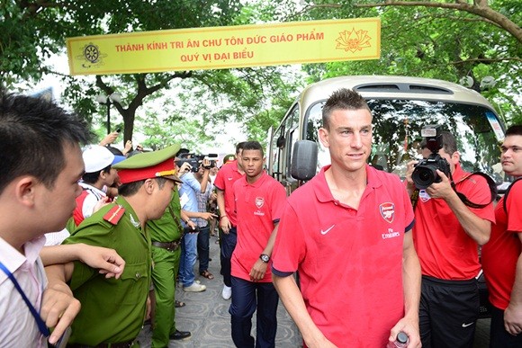 Chùa Trấn Quốc nằm khá gần đại bản doanh Intercontinental của Arsenal và cũng là một địa điểm trong danh sách ghé thăm của các Pháo thủ. Tại đây, ba đại diện của Arsenal là Koscielny, Gnabry Serge và Fabianski tiếp tục nhận được sự quan tâm lớn của người hâm mộ. Trước khi các Pháo thủ đặt chân đến, người hâm mộ đã xếp thành hai hàng chật kín trước cổng chùa để đón tiếp. Ảnh: Koscielny dẫn đầu đoàn biệt phái đi thăm chùa Trấn Quốc.