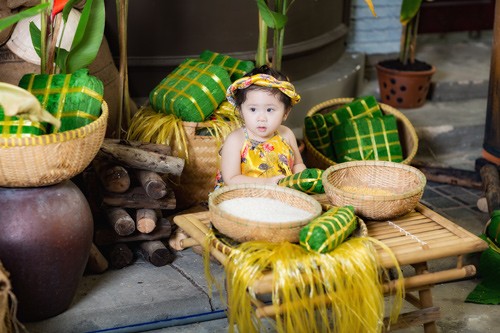 Giữa không gian ngập tràn không khí Tết, hình ảnh " bé gái bụng bự" gần 2 tuổi mặc yếm vàng bên gạo nếp, bánh chưng, bút nghiên, câu đối… “đốn gục” trái tim dân mạng.