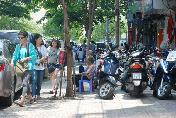 Hàng loạt xe máy xếp hàng ngang, đậu trước cửa hàng tiện dụng trên đường Hải Triều (phường Bến Nghé) tái chiếm vỉa hè, người đi bộ phải né xuống mép đường tìm lối đi.