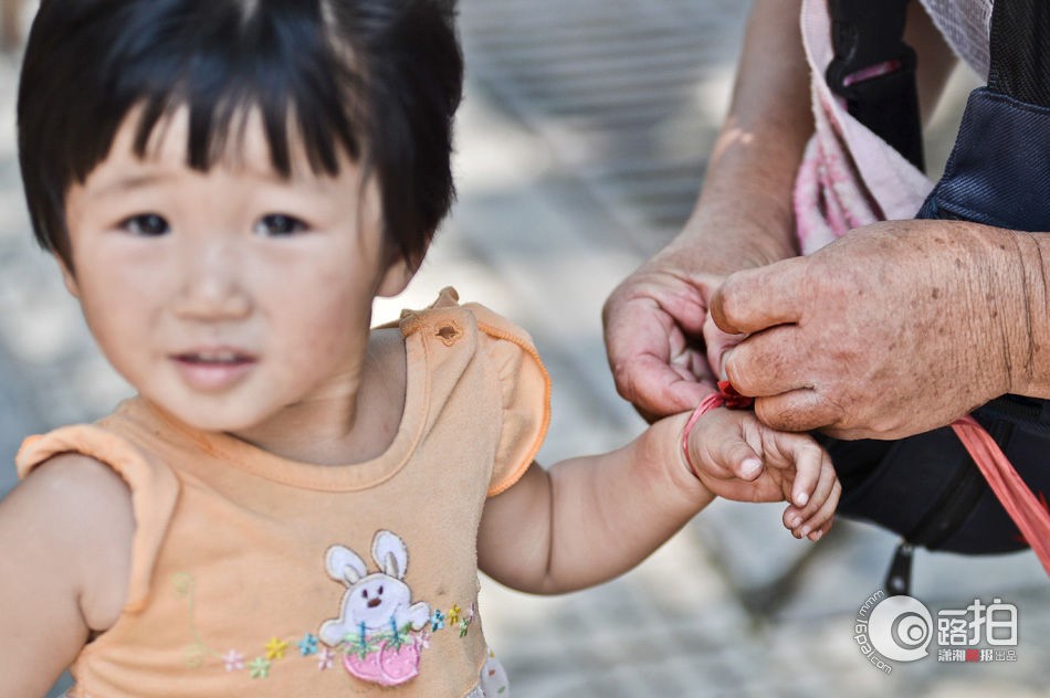 Bé gái Shu Wang, 2 tuổi, phải đi theo ông nội bị tật ở chân, bán rau trên đường phố bởi vì bố và chị gái của cô bé không thể trông hay làm việc sau khi họ bị thương trong một vụ tai nạn ô tô.