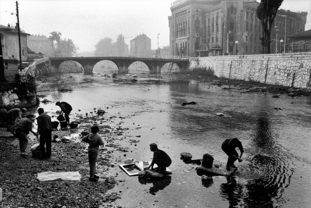 Người dân giặt đồ tại bờ sông ở Sarajevo, Bosnia-Herzegovina khi nước sạch bị cắt ở thành phố này vì chiến tranh, 1993. Cuộc bao vây Sarajevo của quân đội Serbia kéo dài từ tháng 5/4/1992 – 29/2/1996, là một trong những diễn biến quan trọng nhất của  chiến tranh Nam Tư. Ảnh: A. Abbas/ magnum Photos.