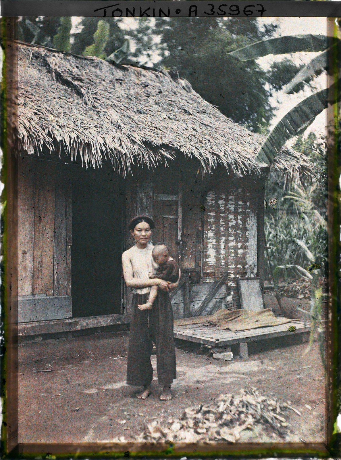 Bà mẹ bế con đứng trước hiên nhà,  Bắc Bộ năm 1921. Ảnh: Léon Busy/Collections.albert-kahn.hauts-de-seine.fr.