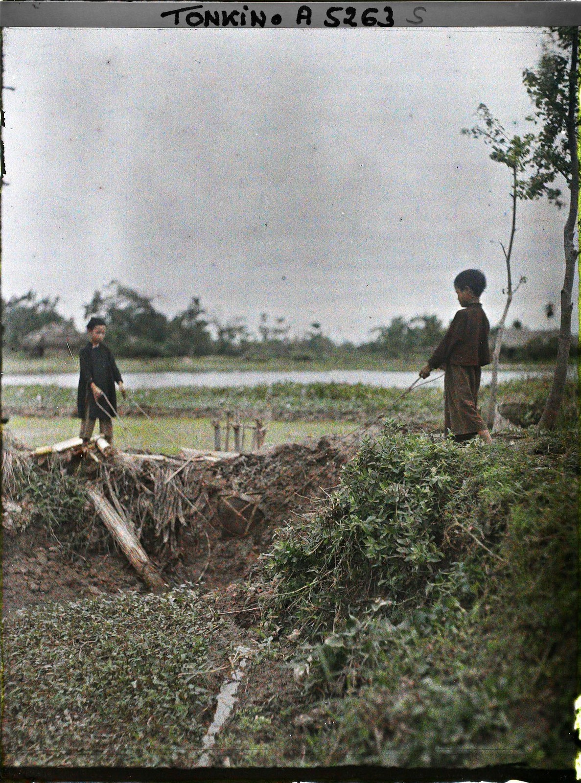 Hai đứa trẻ dùng gàu dây, một loại công cụ tưới tiêu thủ công,  Bắc Bộ năm 1914-1915. Ảnh: Léon Busy/Collections.albert-kahn.hauts-de-seine.fr.