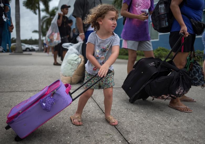 Cô bé Chloe Rosenberger, 3 tuổi, ở Mũi Coral, Florida, kéo lê hành lý theo anh trai và mẹ đến nơi trú bão ở Estero. Hơn 75.000 ở bang Florida đang tìm kiếm nơi ẩn náu tại những nơi trú báo tạm thời. Ảnh: REUTERS